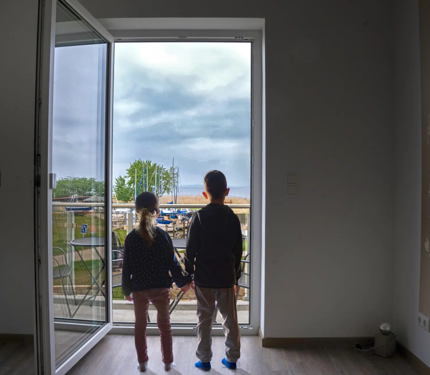 Wasserblick Loddin- Ferienhaus -Deluxe 8, 2 Kinder stehen an der Terrassentür